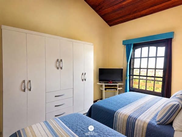 A bedroom with two beds, a TV, and a wardrobe. - Casa Estrela Cond Fechado c Piscina - RJ (Cabo Frio)