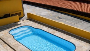 A rectangular swimming pool with a tiled deck surrounding it. - Casa Estrela Cond Fechado c Piscina - RJ (Cabo Frio)
