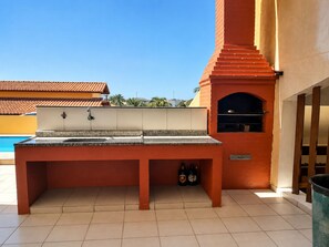 Ein Außenbereich mit Küche, Grill, Spüle und gefliestem Boden.