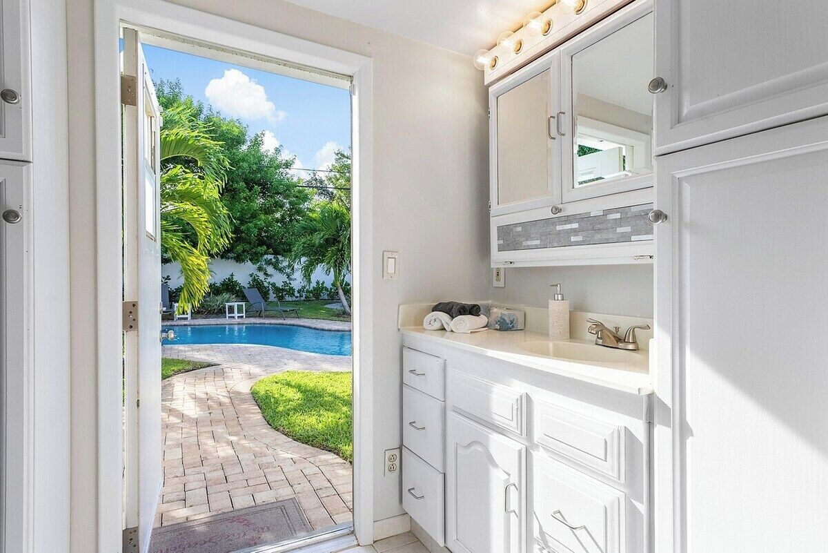 Un baño con vista a una piscina, armarios blancos y salpicadero de azulejos.