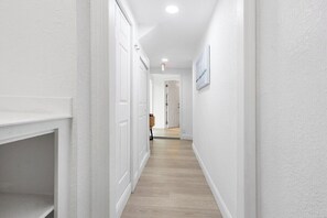 A narrow hallway with white walls and wooden flooring, leading to a door at the end. - Delray Oasis - Heated Pool+Tiki Bar, 4 Kings (Delray Beach)