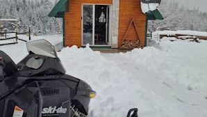 Una cabaña de madera con techo verde, antena parabólica y suelo cubierto de nieve.