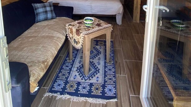 Una habitación acogedora con cama, sofá, una mesita y ventana con cortinas.