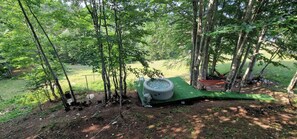 Un jacuzzi en una plataforma verde rodeado de árboles en un área boscosa.