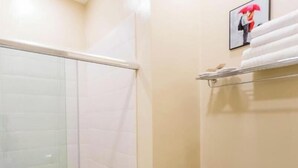 A bathroom with a glass shower enclosure, a toilet, and a towel rack with a framed picture. - Luxury 3BR Apartment by Freedom Squre Tbilisi Georgia (T'bilisi)