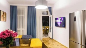 A modern kitchen with a built-in refrigerator, a dining area with a wooden table and yellow chairs, and a large window with blue curtains. - Luxury 3BR Apartment by Freedom Squre Tbilisi Georgia (T'bilisi)