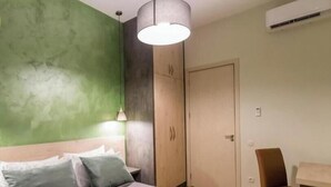 A bedroom with a bed, a desk, a chair, a hanging light fixture, and a door. - Luxury 3BR Apartment by Freedom Squre Tbilisi Georgia (T'bilisi)