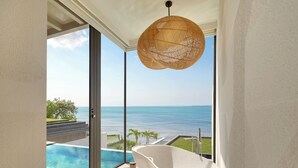A modern bathroom with a freestanding bathtub, a large window, and a view of the ocean.