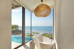 A modern bathroom with a freestanding bathtub, a large window, and a view of the ocean.