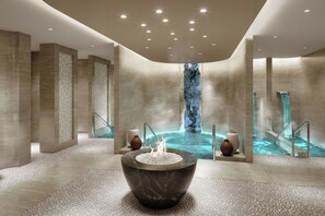 A modern spa area with a central hot tub, a waterfall feature, and a stone-tiled floor. - Delta Hotels By Marriott Jeddah Al Salam (Jeddah)