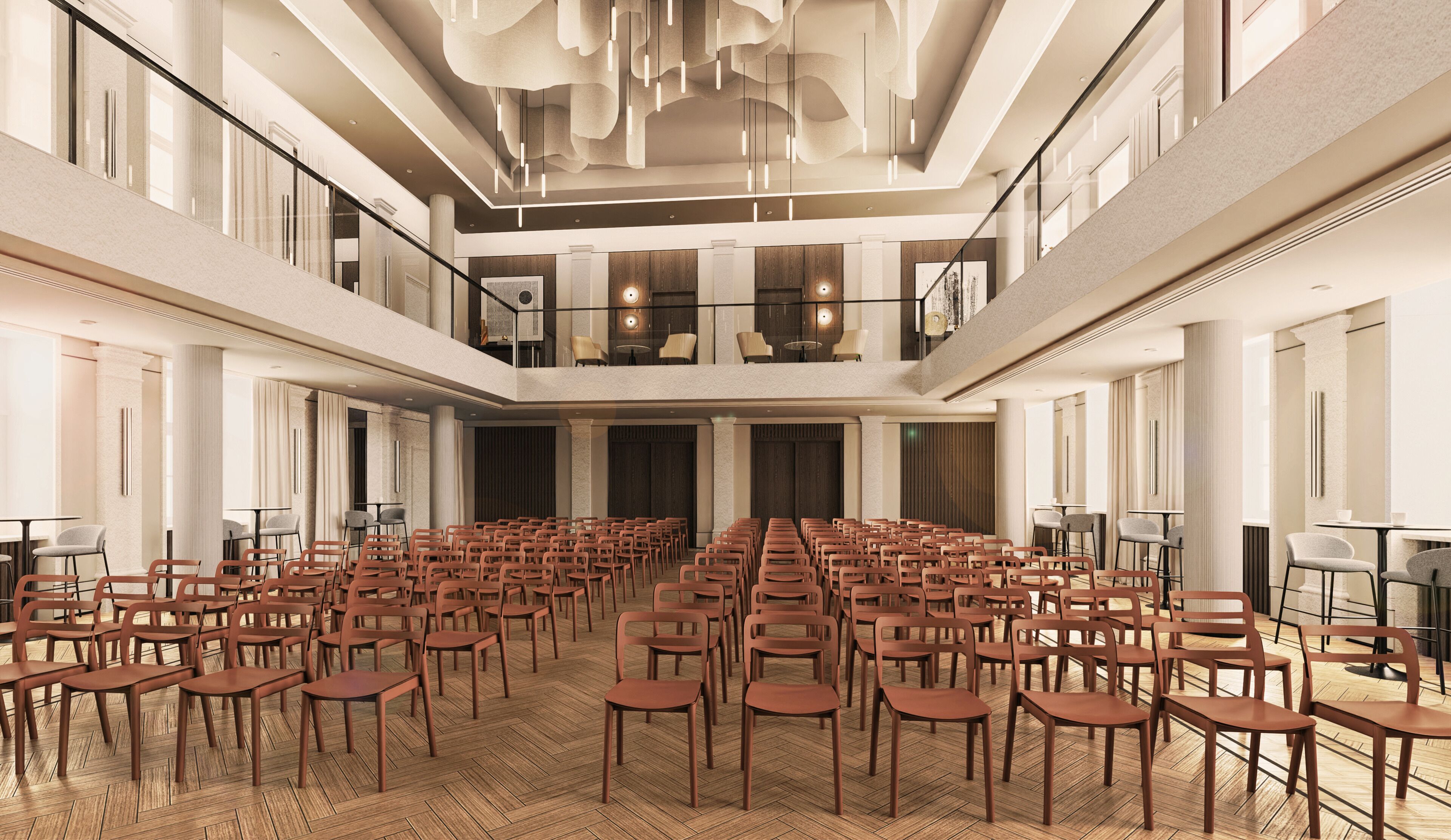 Ein geräumiger Saal mit Reihen von Stühlen, einer hohen Decke mit moderner Beleuchtung und einem Balkon mit Blick auf den Sitzbereich.