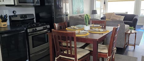Une cuisine moderne avec un coin repas, comprenant un îlot central, des meubles de couleur sombre et un ventilateur de plafond.