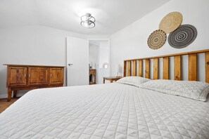 Ein Schlafzimmer mit einem großen Bett, einem Holz-Kopfteil, einem Kleiderschrank und einer Deckenleuchte.