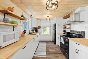 Eine moderne Küche mit weißen Schränken, Holz Arbeitsplatten, einem eingebauten Ofen und einem Kühlschrank.