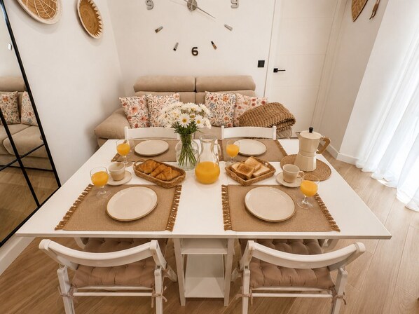 A dining table set for breakfast with plates, glasses, and a pitcher of orange juice. - Seville City Center | Elegant apartment for 4 people. (Sevilla)