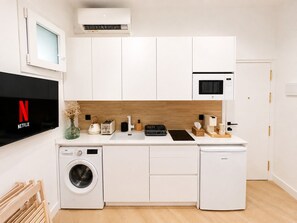 Une cuisine compacte équipée d’un lave-linge, d’un four à micro-ondes et d’un grille-pain.