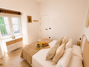 A bedroom with a bed, bedside table, and a window with a view. - Seville City Center | Elegant apartment for 4 people. (Sevilla)