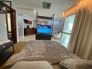 Ein Schlafzimmer mit einem Bett, einem Fernseher, einem Kleiderschrank und Blick auf die Stadt.