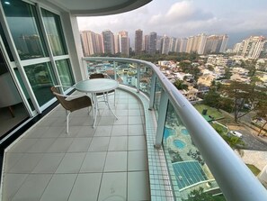 A balcony with a table and chairs, overlooking a cityscape with high-rise buildings. - Apartment facing Barra da Tijuca beach in the former Sheraton. (Rio de Janeiro)