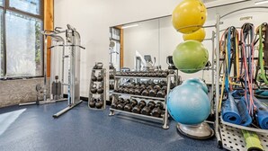 Ein Fitnessstudio mit Trainingsgeräten, Kettlebells, Kurzhanteln und Trainingsbällen.