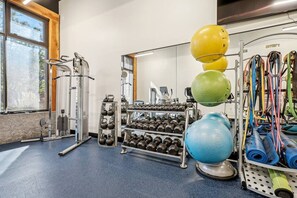 Ein Fitnessstudio mit Trainingsgeräten, Kettlebells, Kurzhanteln und Trainingsbällen.