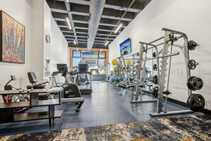 A gym with exercise equipment, a desk with a computer, and a large window with a view. - Luxury Ski In/Out Condo | Pool & Hot tub (Park City)