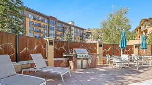 Ein Terrassenbereich im Freien mit Liegestühlen, einem Grill und einer Poolanlage.