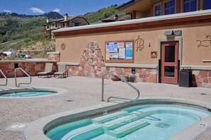 Ein Poolbereich mit mehreren Whirlpools, einer Steinmauer und einem Gebäude mit einem Ausgangeschild.