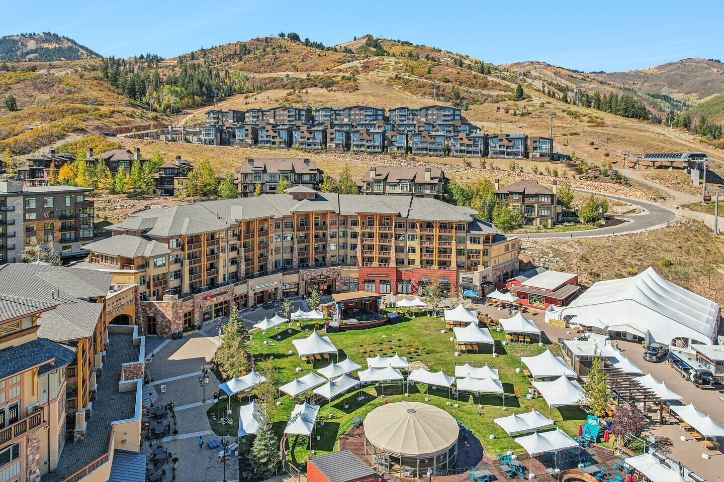 A hotel complex with multiple buildings, outdoor seating areas, and a mountainous backdrop.
