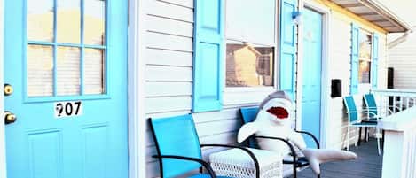 Un bâtiment avec une porte bleue portant le numéro « 07 » et une statue de requin posée sur une chaise.