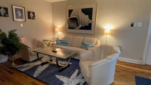 A living room with a sofa set, a coffee table, a lamp, and a large framed artwork on the wall. - The Boat House (Norfolk)