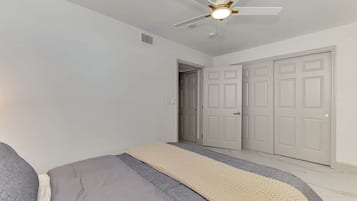 Une chambre à coucher avec un lit, un ventilateur de plafond et une porte.