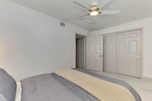 A bedroom with a bed, a ceiling fan, and a door. - Stylish Coastal 1BR | Gulf & Bay Access |Sleeps 4 (Manasota Key)