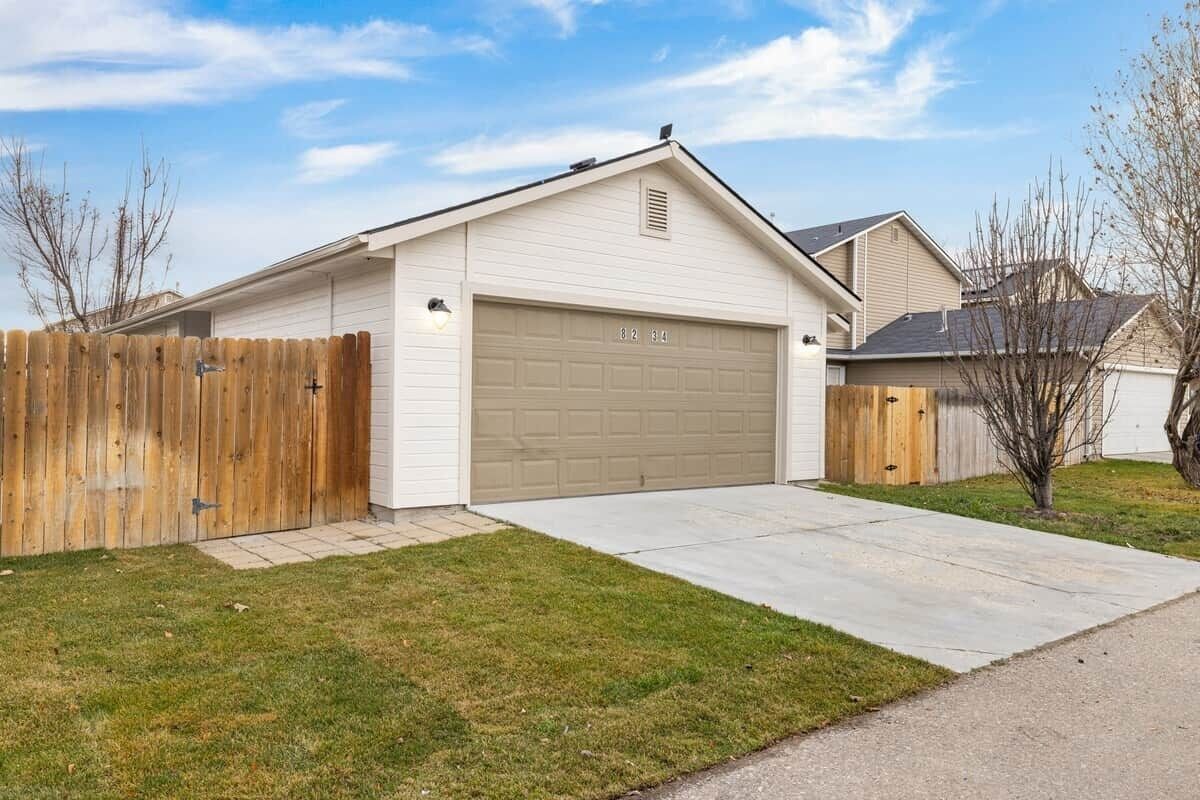 A single-story house with a garage, a wooden fence, and a well-maintained lawn.