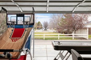 A basketball hoop in a garage with a view of a suburban neighborhood. - Boise Retreat, New, Hot Tub, Game Room (Ada County)