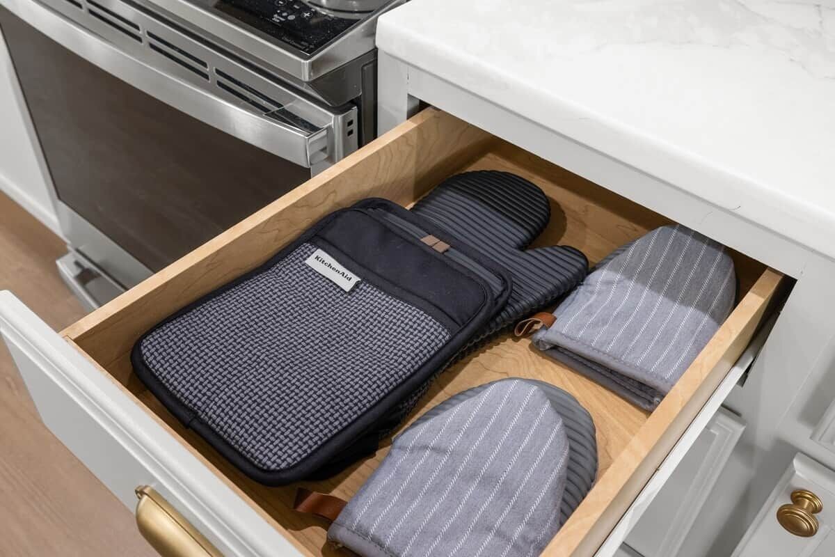 Un tiroir contenant un tapis noir, un tapis à rayures grises et un sac noir portant l’inscription « KitchenAid ».