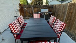 An outdoor patio with a rectangular table and six striped chairs. - Boise Retreat, New, Hot Tub, Game Room (Ada County)