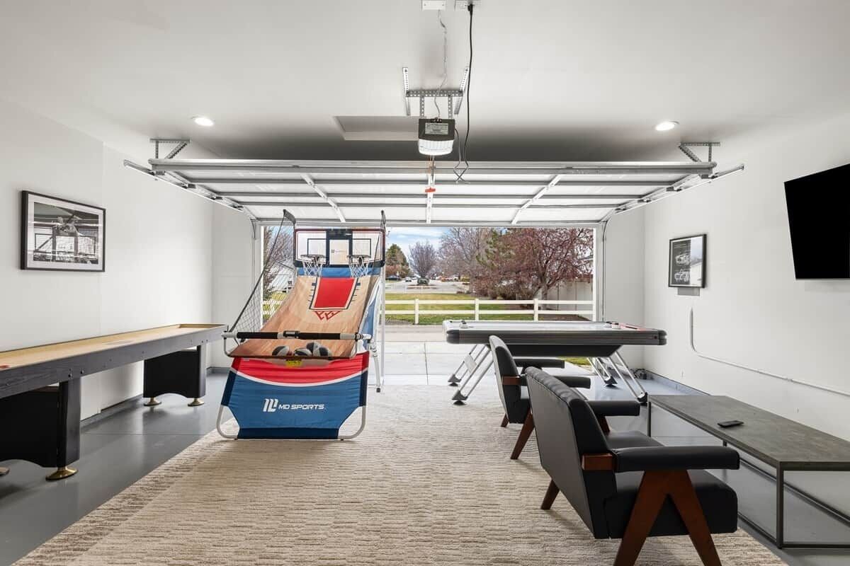 A modern indoor sports area with a ping pong table, a foosball table, and a basketball hoop.