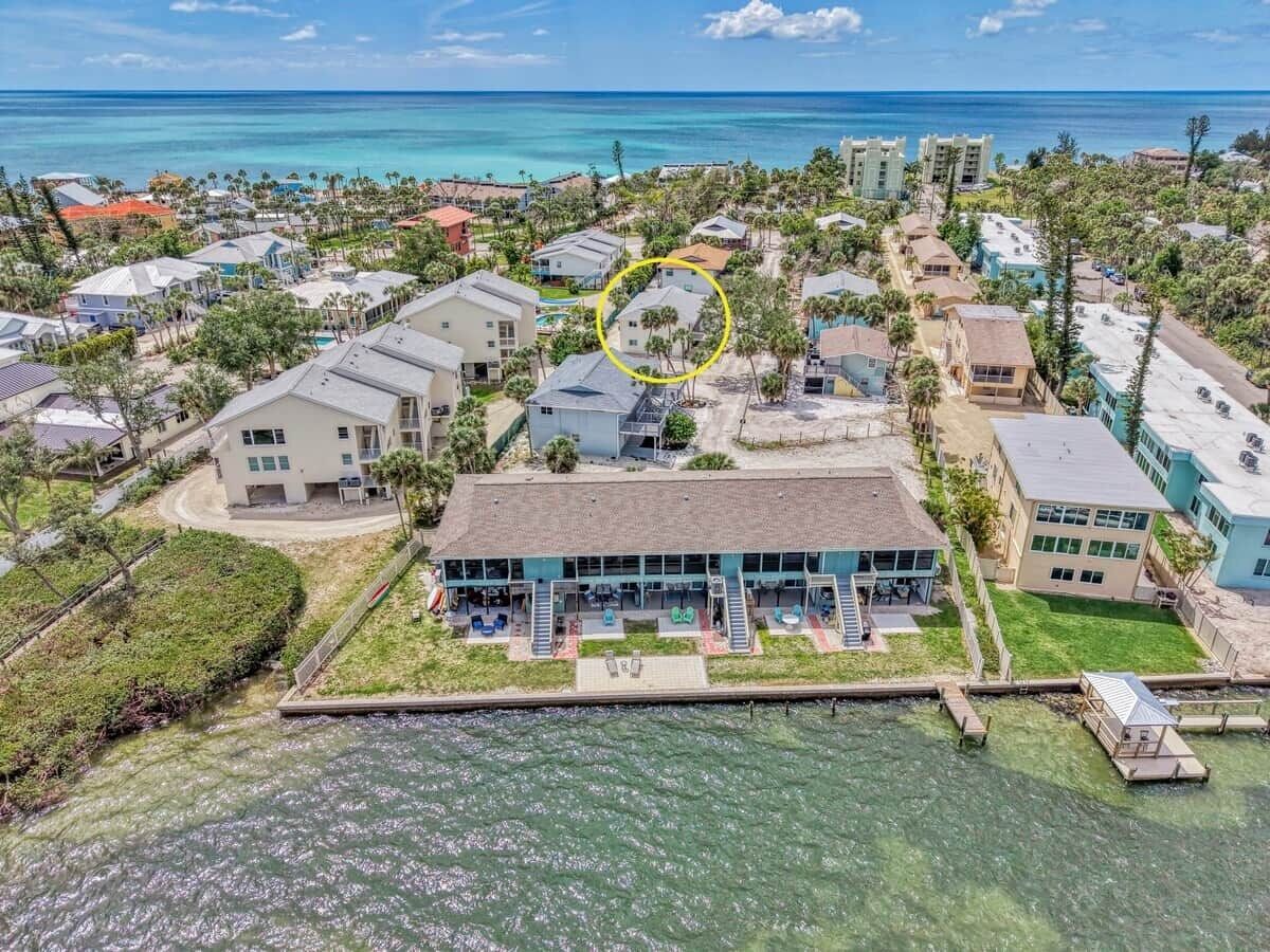 A coastal hotel with a large building, a dock, and a view of the ocean.