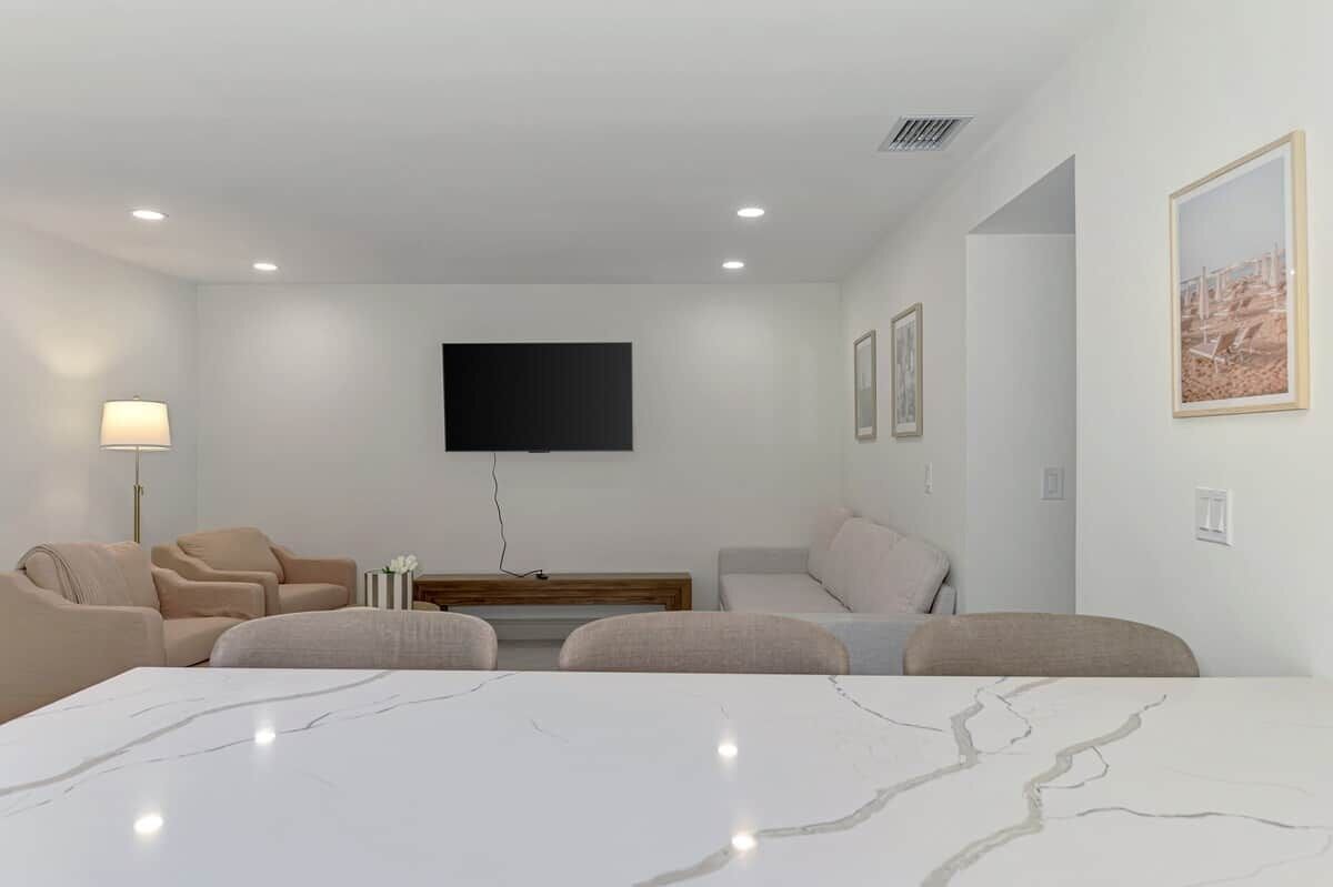 A hotel room with a large bed, two sofas, a TV mounted on the wall, and framed pictures on the wall.