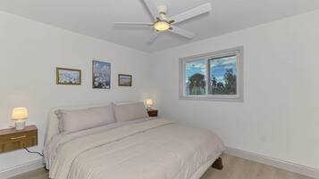 A bedroom with a bed, bedside lamps, a ceiling fan, and a window with blinds.