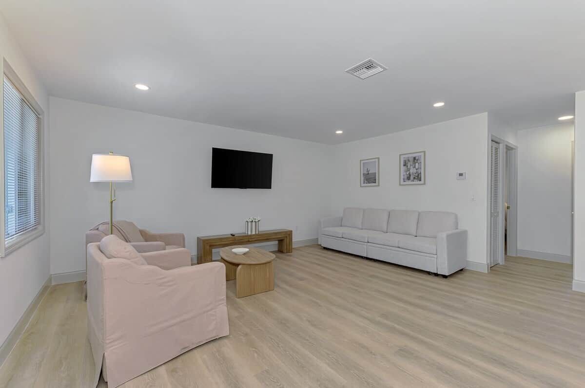 A modern living room with a sofa, a coffee table, and a TV mounted on the wall.