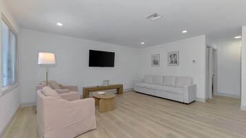 A modern living room with a sofa, a coffee table, and a TV mounted on the wall.