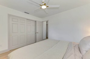 A bedroom with a bed, a ceiling fan, and a door leading to another room. - Coastal 2BR Beach Getaway | Gulf + Bay | Unit B (Manasota Key)
