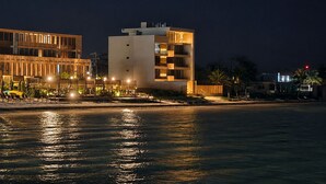 A waterfront hotel with a modern design, featuring balconies and a pool area.
