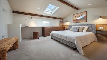 A bedroom with a skylight, a bed with a zebra-patterned bedspread, a desk, and a wall-mounted painting.