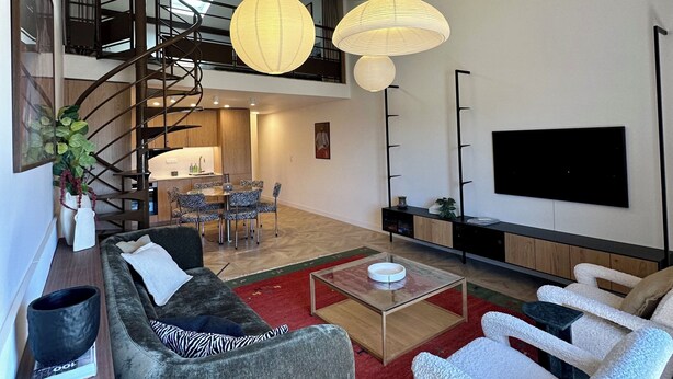 Un salon moderne avec un canapé, des fauteuils, une table basse et un téléviseur.