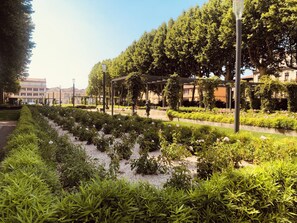 Un jardín ajardinado con senderos, bancos y una pérgola.