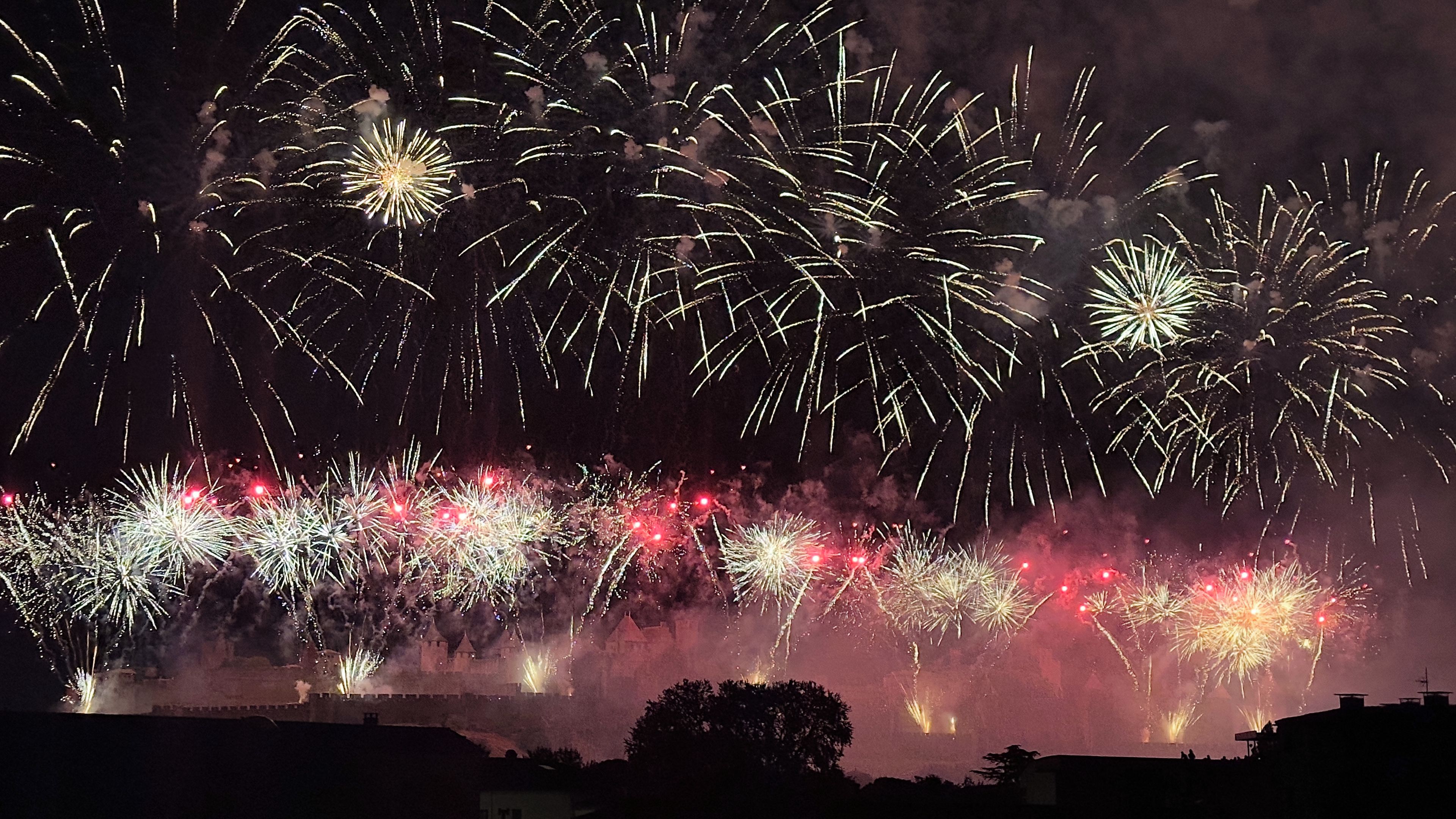 A nighttime view of fireworks over a castle-like structure.