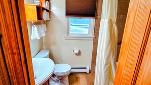 A compact bathroom with a toilet, a small window, and a shower curtain.